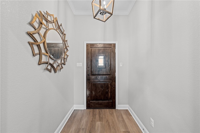 foyer with a chandelier, crown molding, and light hardwood / wood-style floors