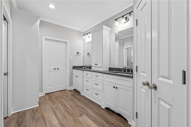 full bath featuring wood finished floors, double vanity, ornamental molding, and a sink