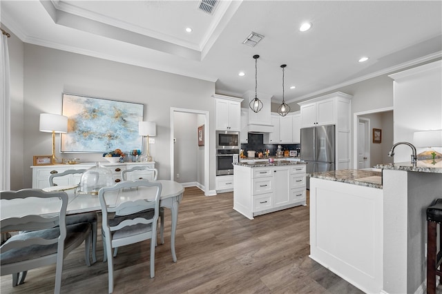 kitchen with light stone counters, visible vents, stainless steel appliances, and wood finished floors