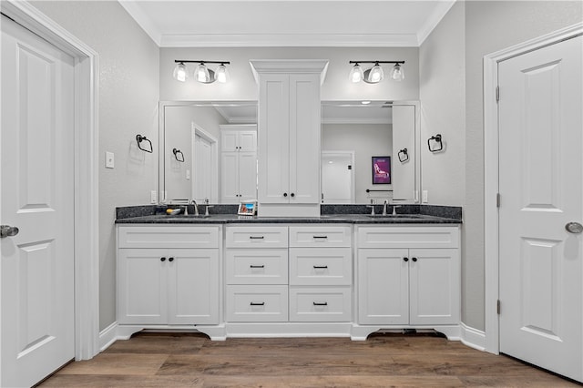 bathroom with a sink, double vanity, crown molding, and wood finished floors