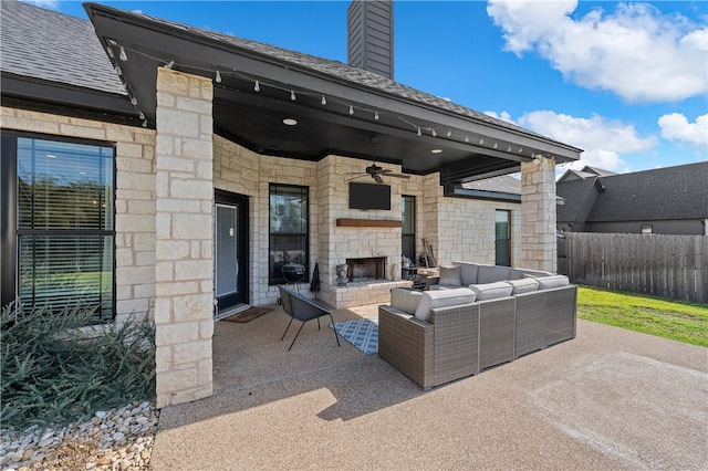 view of patio / terrace with an outdoor living space with a fireplace, fence, and a ceiling fan