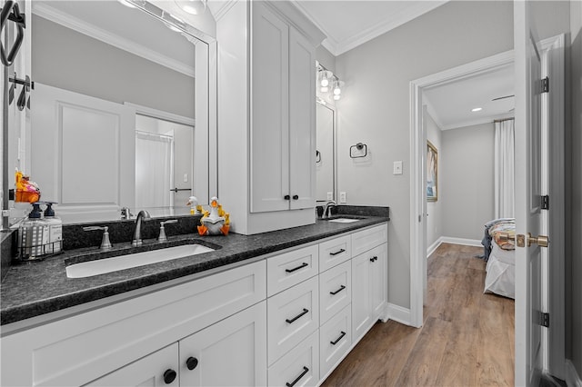 bathroom featuring ornamental molding, a sink, and wood finished floors