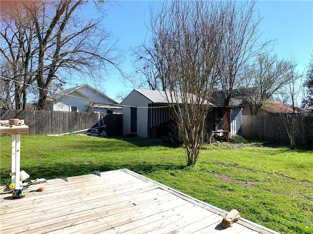 wooden terrace featuring an outbuilding, a fenced backyard, and a lawn