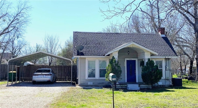 view of front of property with a detached carport, a shingled roof, gravel driveway, a front lawn, and fence