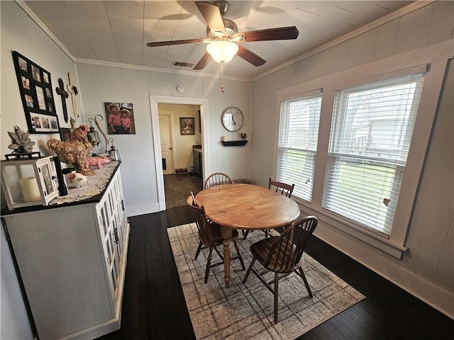 dining space with visible vents, dark wood-type flooring, ornamental molding, and a ceiling fan