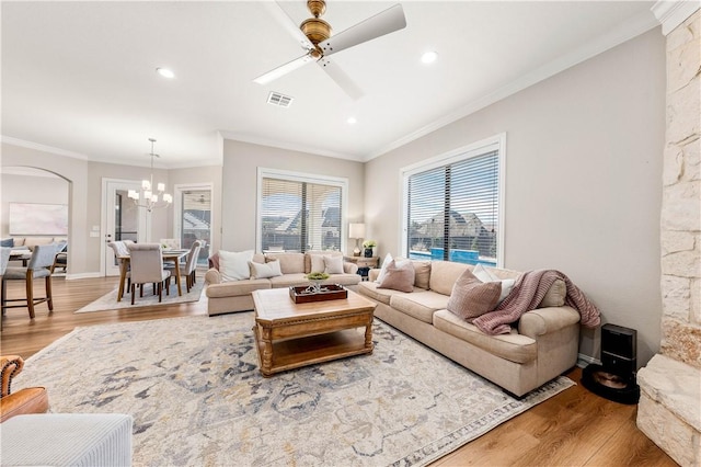 living room with ceiling fan with notable chandelier, ornamental molding, and hardwood / wood-style floors