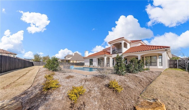 rear view of property featuring a balcony and a fenced in pool