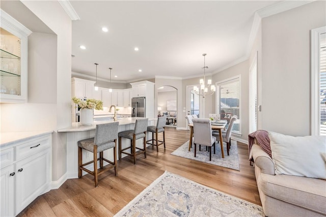 dining area with light hardwood / wood-style flooring, crown molding, and an inviting chandelier