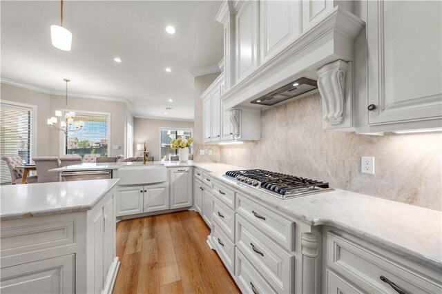 kitchen with appliances with stainless steel finishes, decorative light fixtures, white cabinetry, premium range hood, and kitchen peninsula