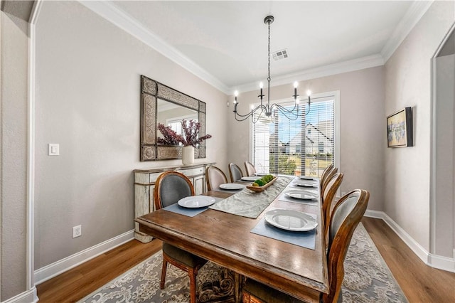 dining space with a notable chandelier, ornamental molding, and hardwood / wood-style floors