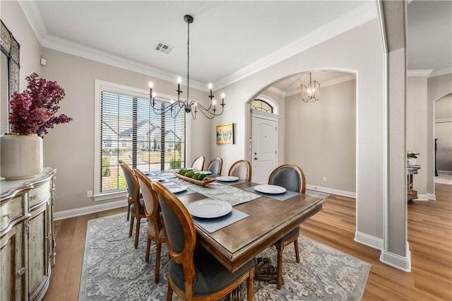 dining area with a chandelier, crown molding, and light hardwood / wood-style flooring