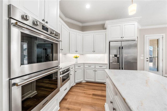 kitchen with pendant lighting, light hardwood / wood-style flooring, appliances with stainless steel finishes, ornamental molding, and white cabinets