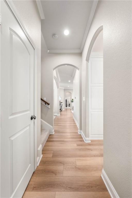 corridor with ornamental molding and light hardwood / wood-style flooring