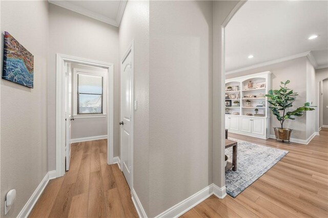 hallway featuring crown molding and light hardwood / wood-style flooring