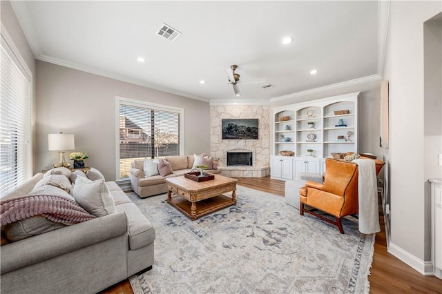 living room featuring ceiling fan, wood-type flooring, crown molding, and a fireplace