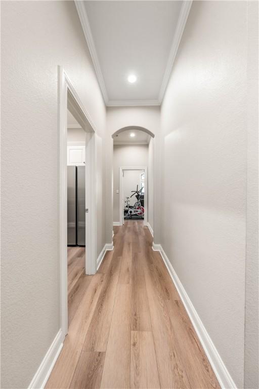 hallway featuring crown molding and light hardwood / wood-style floors