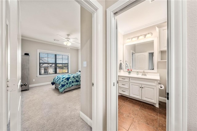 carpeted bedroom with ensuite bath, ceiling fan, crown molding, and sink