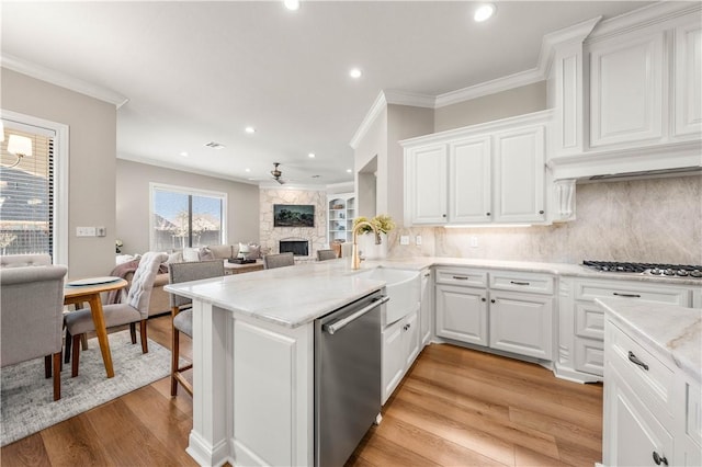 kitchen with white cabinetry, kitchen peninsula, ceiling fan, appliances with stainless steel finishes, and decorative backsplash