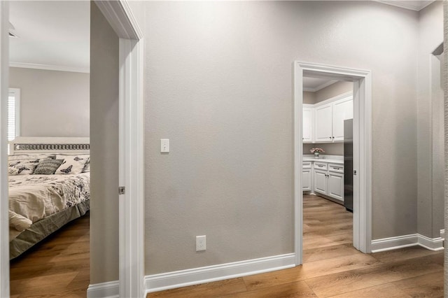 hallway featuring crown molding and light hardwood / wood-style flooring