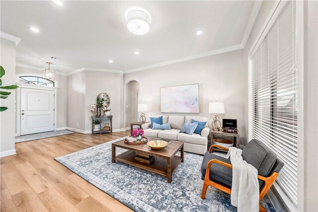 living room featuring an inviting chandelier, crown molding, and light hardwood / wood-style flooring