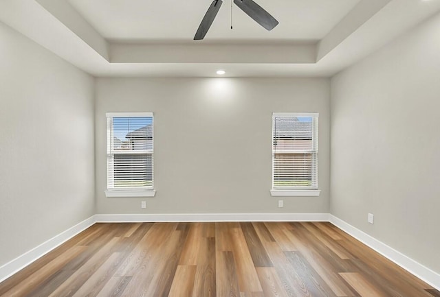 spare room featuring a raised ceiling, ceiling fan, and wood-type flooring