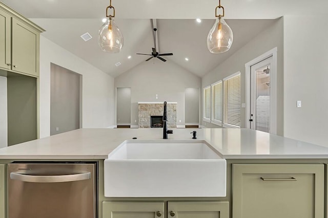 kitchen with ceiling fan, sink, green cabinetry, a stone fireplace, and lofted ceiling