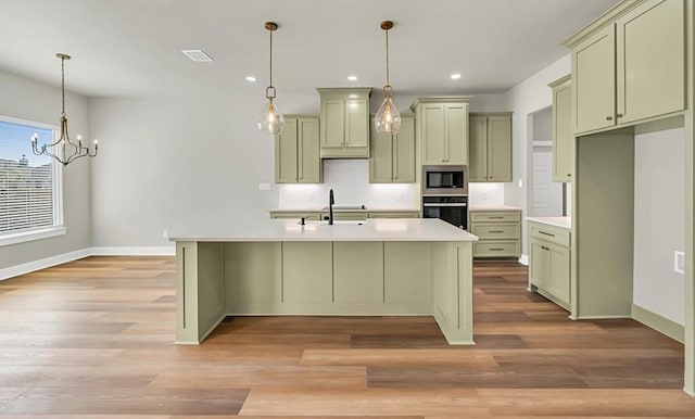 kitchen featuring light hardwood / wood-style floors, a kitchen island with sink, appliances with stainless steel finishes, and an inviting chandelier