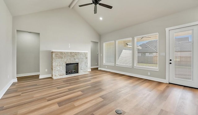 unfurnished living room with beam ceiling, ceiling fan, light hardwood / wood-style flooring, high vaulted ceiling, and a fireplace