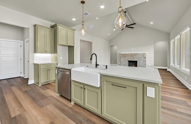 kitchen with lofted ceiling, a kitchen island with sink, sink, stainless steel dishwasher, and dark hardwood / wood-style flooring