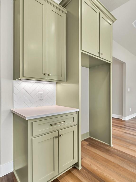 kitchen featuring decorative backsplash, light hardwood / wood-style flooring, and green cabinetry