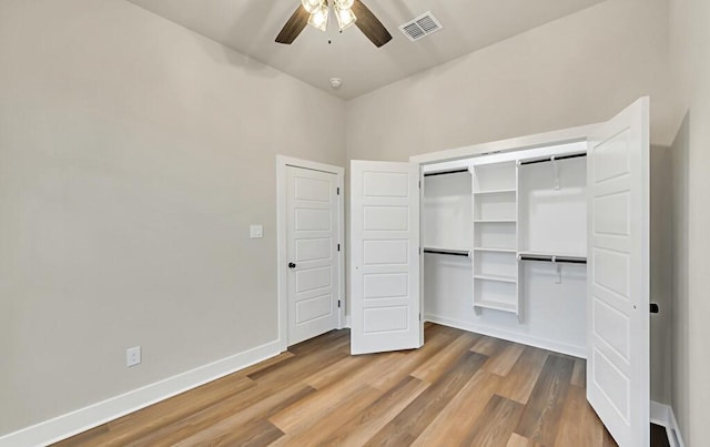 unfurnished bedroom featuring hardwood / wood-style flooring, ceiling fan, a towering ceiling, and a closet