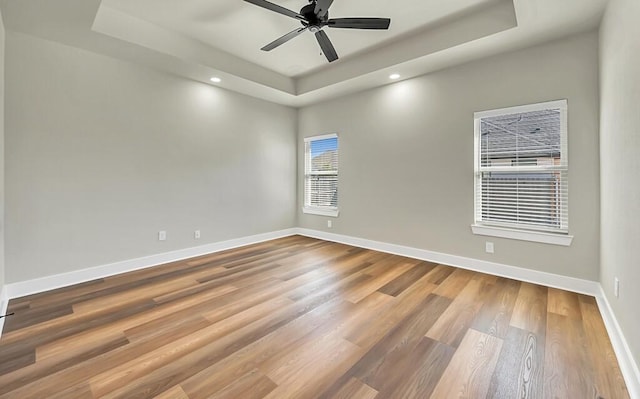 unfurnished room with a tray ceiling, ceiling fan, and hardwood / wood-style flooring