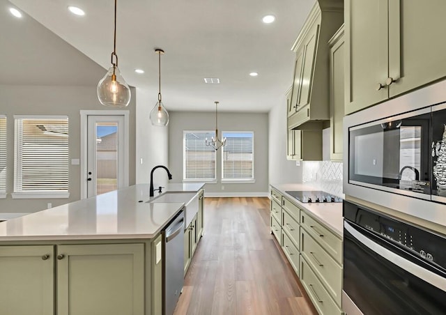 kitchen featuring hanging light fixtures, sink, stainless steel appliances, and a kitchen island with sink