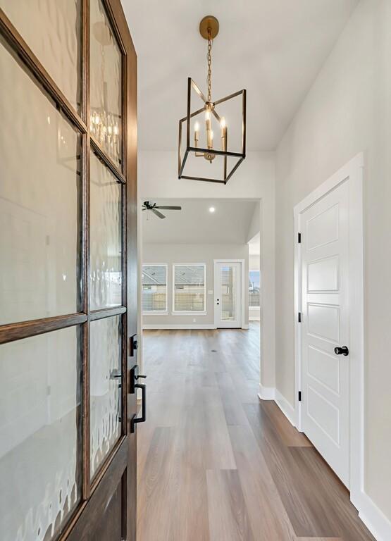 foyer with hardwood / wood-style floors and ceiling fan with notable chandelier