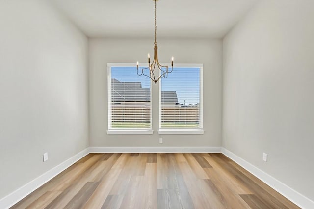 unfurnished dining area featuring hardwood / wood-style flooring and a notable chandelier