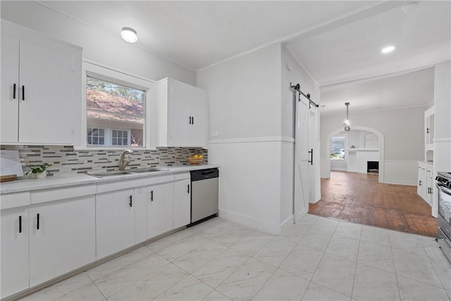 kitchen with a barn door, sink, white cabinets, and appliances with stainless steel finishes