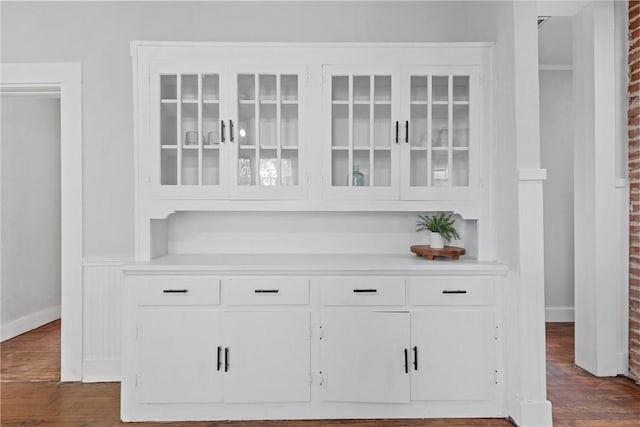 bar with white cabinets, dark hardwood / wood-style floors, and brick wall