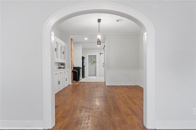 corridor with light wood-type flooring and ornamental molding