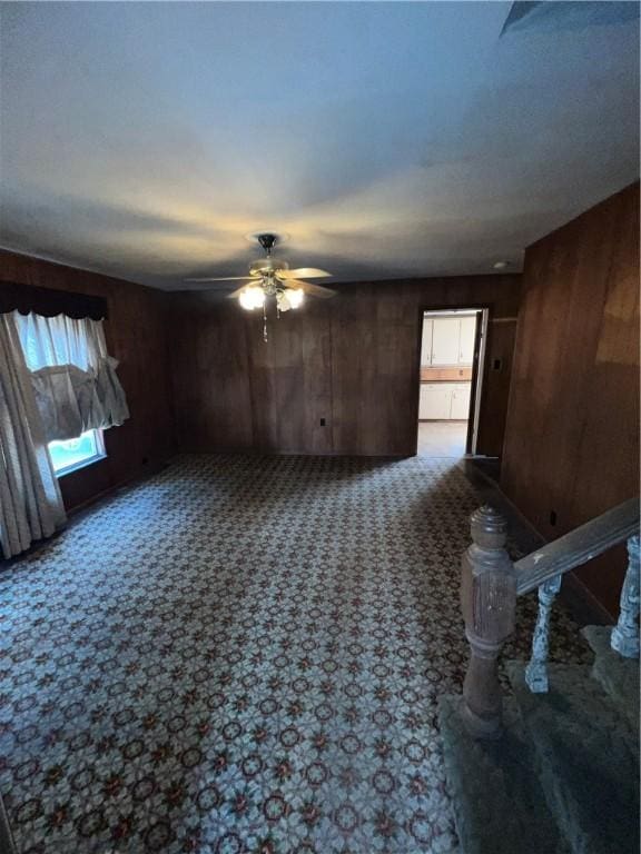 unfurnished room featuring wood walls, carpet, and ceiling fan