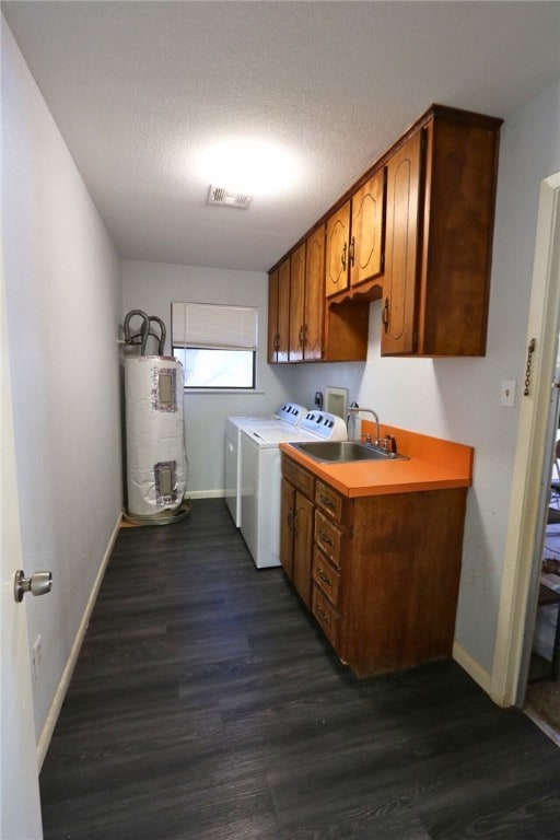 laundry area featuring cabinets, a textured ceiling, electric water heater, washing machine and dryer, and dark hardwood / wood-style floors