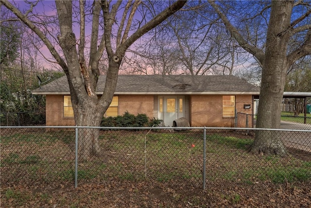 view of front of home featuring an attached carport, brick siding, roof with shingles, and a fenced backyard