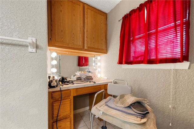 bathroom with tile patterned floors, vanity, and a textured wall