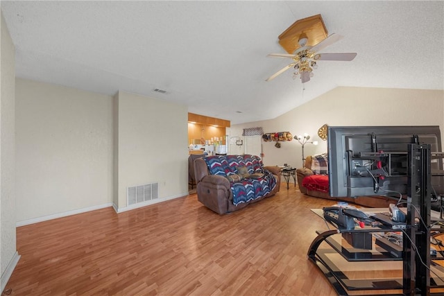 living area featuring wood finished floors, a ceiling fan, visible vents, and vaulted ceiling