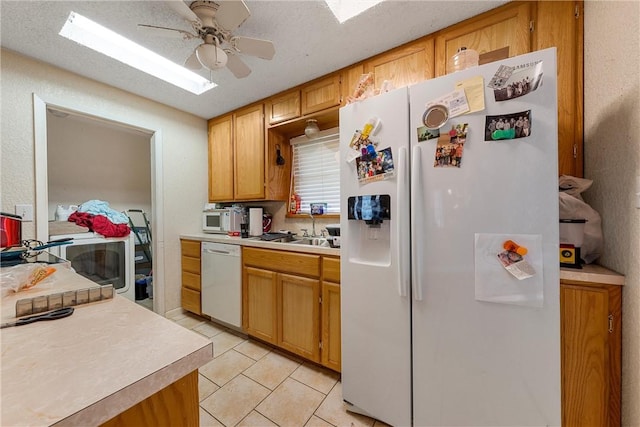 kitchen with a sink, white appliances, light countertops, light tile patterned floors, and ceiling fan