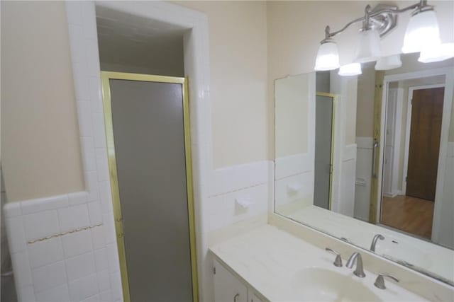 bathroom featuring vanity, a shower with shower door, and tile walls