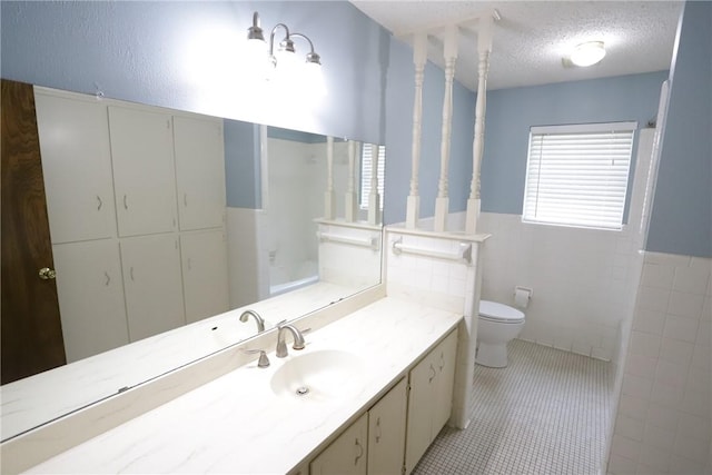 bathroom with tile patterned flooring, vanity, a textured ceiling, and tile walls