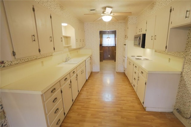 kitchen featuring white dishwasher, light hardwood / wood-style floors, white cabinetry, and sink