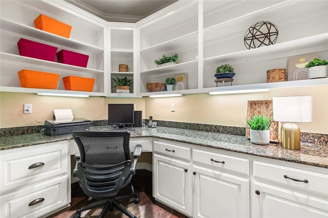 office space with built in desk, dark wood-type flooring, and ornamental molding