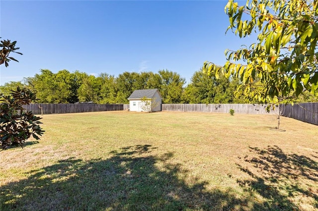 view of yard with an outbuilding, a storage unit, and a fenced backyard