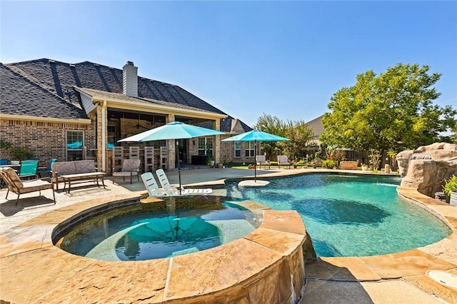 view of swimming pool with a patio, fence, a pool with connected hot tub, and an outdoor hangout area